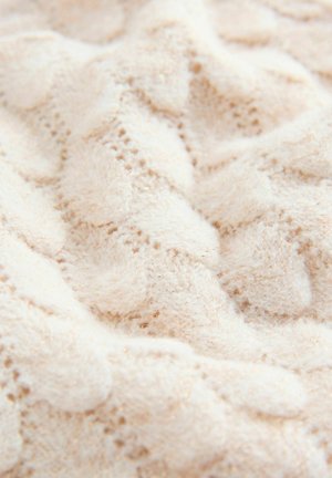 Hvid strikket stof med en blød, fluffy tekstur med et bølget mønster og subtile gyldne tråde vævet ind.