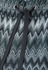 Tissu tricoté zigzag noir et blanc avec cordon noir passé à travers des œillets métalliques en haut.