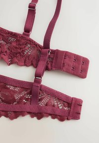 Dark pink lace bra straps with adjustable hooks and metal sliders on a light background.