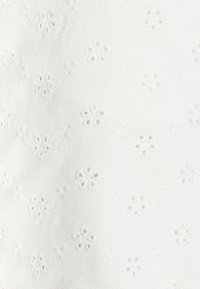 Tissu blanc avec une broderie florale complexe, de petites découpes, une surface texturée et un motif à côtes subtil sur l'ensemble.