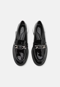 Černé lakované kožené loafers s lesklým povrchem, stříbrným řetízkovým akcentem a texturovanou podrážkou. Má kulatou špičku a branding DKNY.