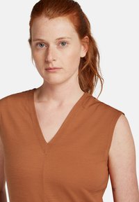 Mouwloze V-hals top in roestbruin, gemaakt van soepele stof, met een eenvoudig ontwerp, een nette halslijn en subtiele stikdetails.