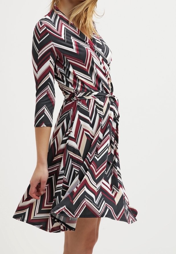 F Wrap klänning med en chevronmönster i vinröd, svart och kräm, med trekvartsärmar och ett knytbälte, tillverkad av ett mjukt tyg.