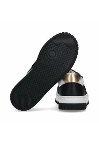 Sneaker in bianco e nero che mostra una suola in gomma testurizzata, dettagli dorati sul tallone e una parte superiore liscia con sovrapposizioni distintive.