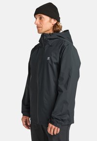 Schwarze wasserdichte Herrenjacke mit verstellbarer Kapuze, Reißverschluss, elastischen Bündchen und kleinem Logo auf der Brust.