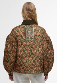 Casaco bomber acolchoado em verde com tecido estampado em flores nas cores laranja e rosa. Apresenta um colarinho de veludo cotelê e um emblema da marca nas costas.