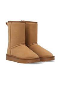 Beżowe zamszowe botki do kostki z okrągłym noskiem, przeszyciami i gumową podeszwą. Charakteryzują się miękką fakturą i średnią wysokością.