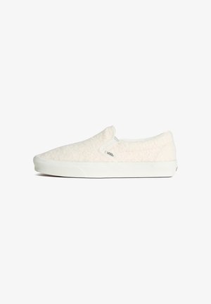 Zapatillas slip-on con parte superior de tejido crema texturizado, suela de goma blanca y detalles de costura mínimos. Diseño clásico y de perfil bajo.