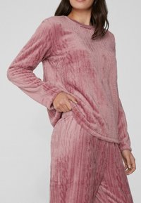 Rosa, kuschelige Loungewear-Set mit einem strukturierten Pullover mit gerippten Akzenten und passenden Hosen, beide aus weichem, gemütlichem Stoff.