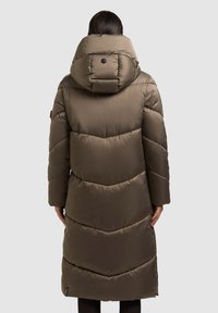 Pikk pruun sulejope suure kapuutsiga, mis on ruuduline, elastsete varrukaservadega ja seljal kaela lähedal asuva logonupuga.