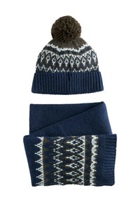 Jūrininkų mėlynas megztas skrybėlė su ruduojo pom-pomu, puošiančiu geometrinį raštą, derinta su atitinkamu šaliku, demonstruojančiu panašius dizainus ir tekstūrą.