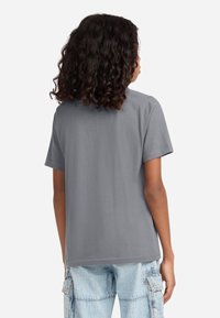 Grå bomulds T-shirt med korte ærmer, afslappet pasform og et enkelt design. Bemærkelsesværdig detalje inkluderer stikninger langs skuldersømmene.