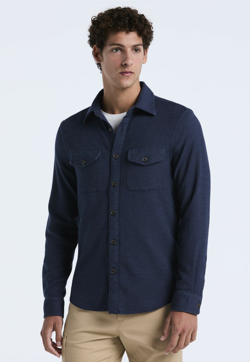 Donkerblauw overhemd met knopen, gemaakt van gestructureerde stof, met twee borstzakken, een gespreide kraag en zichtbare knoopsluitingen.