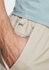 Light blue top and beige shorts, featuring an elastic waistband, pocket with tab, and a textured cotton fabric, close-up view.
