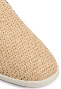 Lättviktig sneaker med ovandel i vävd naturlig fiber i beige, med en slät vit gummisula och rund tådesign.