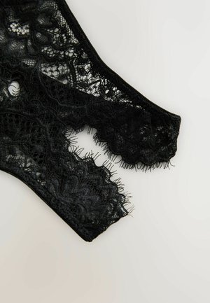 Schwarze Spitzenunterwäsche mit komplizierten Mustern und gezackten Kanten, die transparente Texturen und ein zartes Finish aufweist.