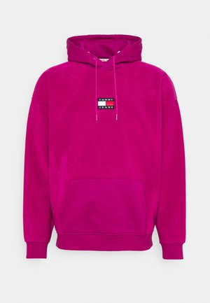 Magenta Hoodie mit Fronttasche, verstellbarem Kordelzug an der Kapuze, gerippten Bündchen und kleinem Tommy Jeans Logo-Patch auf der Brust.