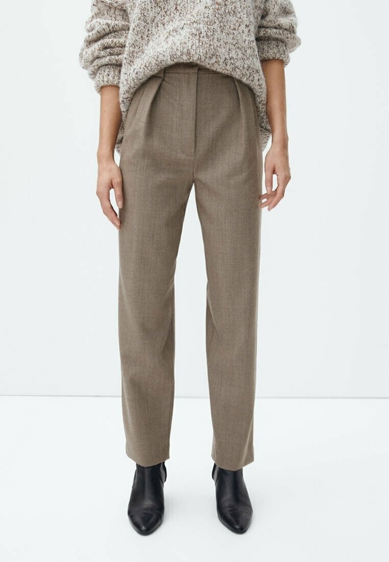 Pantalon marron sur mesure à jambe droite, avec des plis à l'avant et une texture lisse. Associé à des bottines noires et un pull léger en maille.