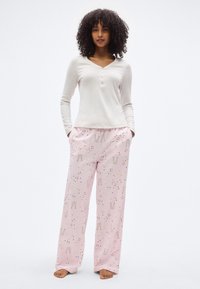 Μπλούζα Henley με μακριά μανίκια σε μπεζ απόχρωση, με τρία κουμπιά, συνδυασμένη με ροζ παντελόνι πιτζάμας με σχέδιο από ποτήρια σαμπάνιας και κομφετί.