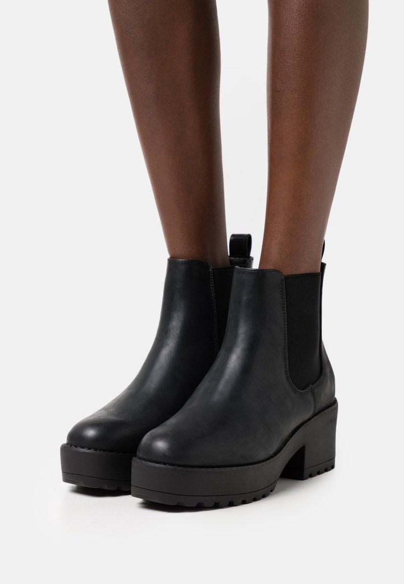 Botas de tobillo de cuero negro con paneles laterales elásticos, un acabado texturizado, puntera redondeada y un tacón de plataforma gruesa.
