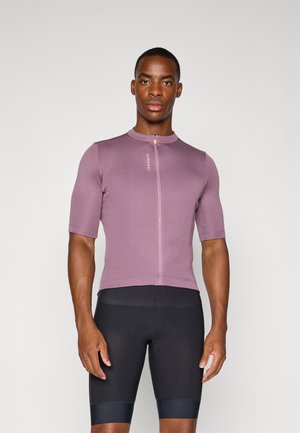 Enganliegendes Radtrikot mit kurzen Ärmeln in gedämpftem Lila, ausgestattet mit einem Reißverschluss auf der Vorderseite, einem abgerundeten Kragen und Logodetails. Kombiniert mit schwarzen Fahrradhosen.