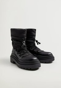 Bottes noires avec une tige rembourrée, un laçage et une semelle épaisse. Fabriquées en cuir et en matériaux synthétiques. Accents texturés visibles.