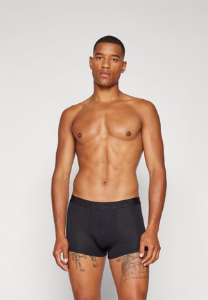 Zwarte boxershorts met een geweven tailleband waarop de merknaam staat. De stof lijkt soepel en rekbaar, wat bijdraagt aan het aansluitende ontwerp.