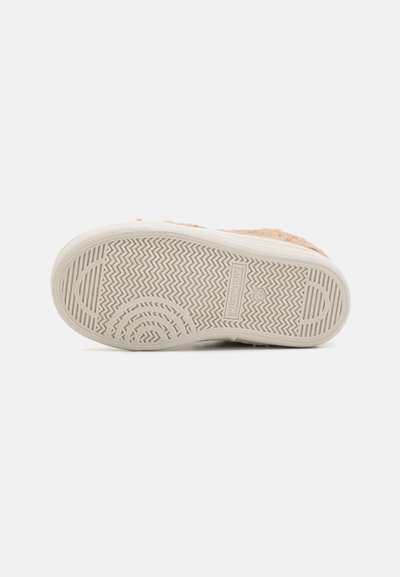 Shoe sole with a textured rubber material, featuring a zigzag pattern and circular accents, in light beige with "MADE IN ITALY" label.