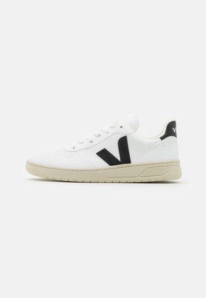 Biały niski sneaker z beżową podeszwą, czarne logo "V" z boku i czarny pasek na pięcie z białym oznakowaniem.
