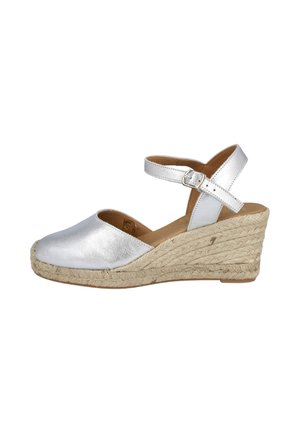 Sandalia de cuña de cuero plateado con puntera cerrada, tira en el tobillo con hebilla y suela trenzada de fibra natural.