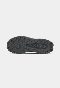 Suela de zapato de goma negra con profundas garras y patrones angulares, diseñada para tracción y durabilidad, con una línea de agarre central.