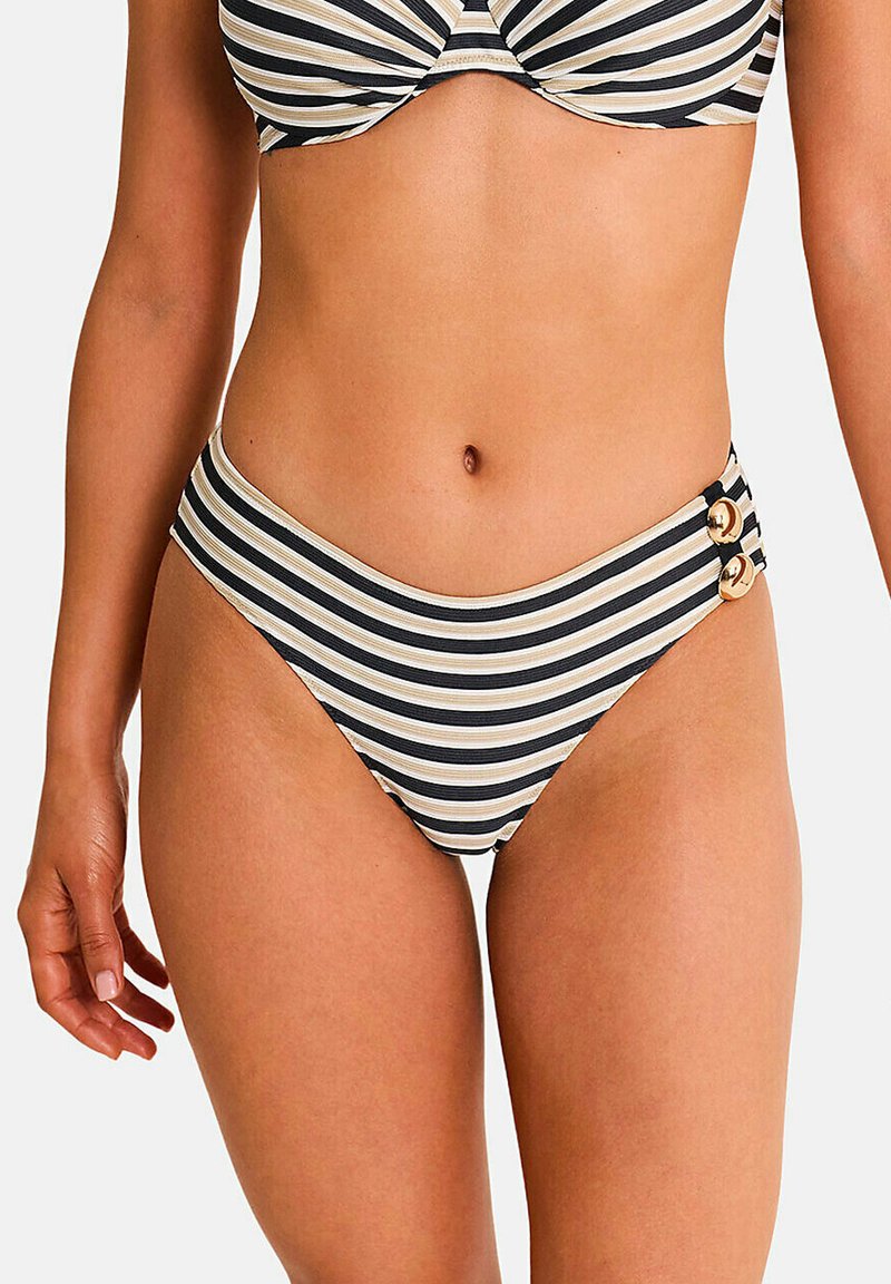 Femme portant un bas de bikini rayé horizontalement noir, blanc et beige avec deux boutons dorés décoratifs sur la hanche droite.