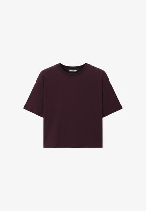 T-shirt court uni violet foncé à manches courtes avec un col rond sur fond blanc.