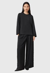 Svart långärmad topp och vida byxor i ett lent tyg. Har rund halsringning och minimala sömnadsdetaljer för en elegant look.