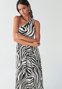 Ensorts sort-hvid zebra print kjole med et enkelt skulderdesign, draperet stof og flydende snit. Glat tekstur, med en tætsiddende krop og en afslappet nederdel.