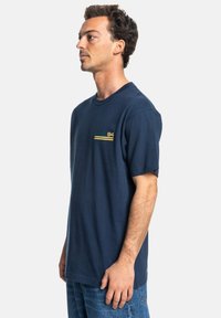 Navy blue cotton t-shirt featuring a crew neck, short sleeves, and a small graphic on the chest in green, yellow, and white.
