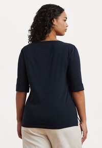 Tricou bleumarin cu mânecă până la cot, cu decolteu rotund, fante laterale și textură netedă. Design simplu, potrivit pentru îmbrăcăminte casuală.