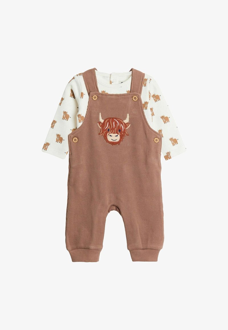 Braune Corduroy-Latzhose mit einem Patch in Form eines Highland-Rinds, kombiniert mit einem cremefarbenen Langarmshirt mit kleinen braunen Kuhmotiven.