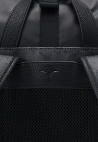 Zaino nero con parte superiore in pelle testurizzata, sezione inferiore in rete e un logo goffrato sottile. Spallacci regolabili in materiale coordinato.