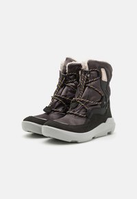Schwarze Winterstiefel mit einem plüschigen Innenfutter, mehrfarbigen Schnürsenkeln und einer kontrastierenden weißen Sohle. Sie verfügen über eine abgerundete Zehenpartie und einen gepolsterten Knöchel.
