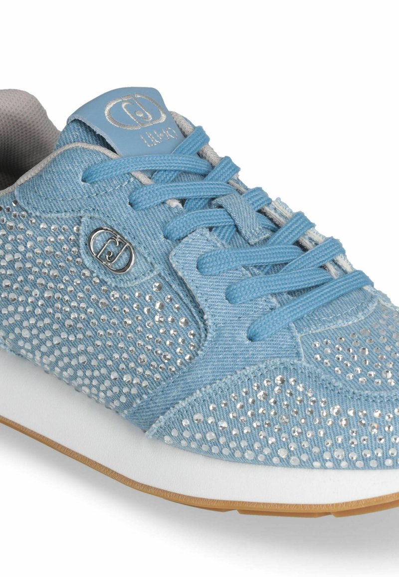 Baskets bleu clair en matière denim, présentant un motif en strass sur les côtés, semelle blanche et languette grise avec accent de logo.