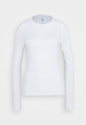 Chemise blanche à manches longues en tissu doux, avec un col rond, un design ajusté et un logo bleu sur la poitrine. Texture lisse.