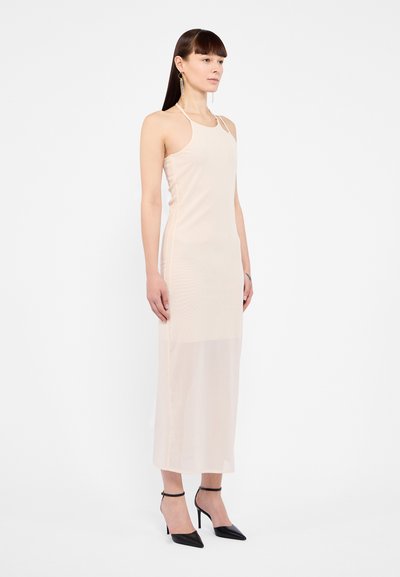 Light pink, fitted halter dress with a sheer fabric, reaching mid-calf. Paired with black pointed-toe heels and ankle straps.
