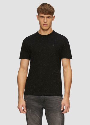 Zwarte t-shirt met korte mouwen en een gesprenkeld patroon, ronde halslijn en een klein logo op de borst. Draagt met lichtgrijze versleten jeans.
