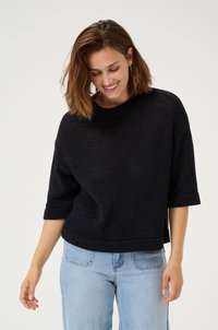 Black knit sweater with short sleeves, textured fabric, ribbed neckline, and hemline, paired with light blue denim jeans.
