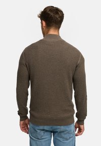 Brun strikket sweater med rund hals og lange ærmer, der har et struktureret mønster samt ribbede manchetter og kant.