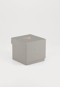 Caixa de armazenamento texturizada cinza com um logótipo dourado triangular na tampa, apresentando um design simples e um fecho de aba na parte da frente.