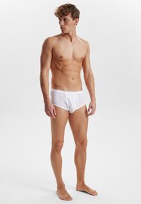 Hvide mesh-trusser med et tætsiddende design, blødt stof og en kontureret pouches. Den elastiske linning øger komforten og pasformen.