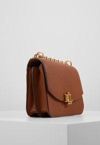 Brązowa torebka skórzana o teksturowanym wykończeniu. Posiada złoty łańcuszek oraz zapięcie z wytłoczonym logo z przodu.