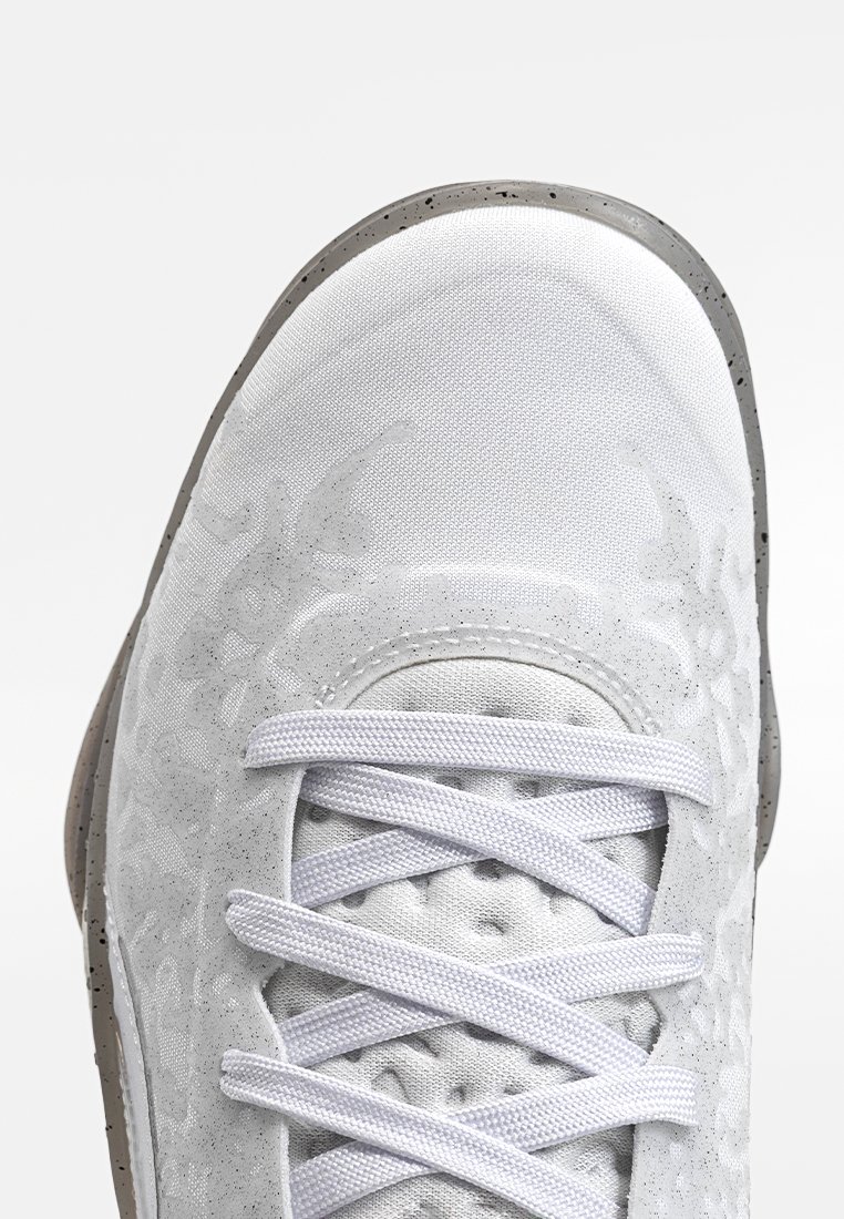 Weißer Sportschuh mit einem strukturierten Stoffobermaterial, hellgrauen Akzenten und einer Gummisohle mit gesprenkeltem Detail. Verfügt über flache weiße Schnürsenkel.